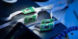 Green computer microchips Four green computer microchip panels lie side-by-side on one edge against a black backdrop in a computer.