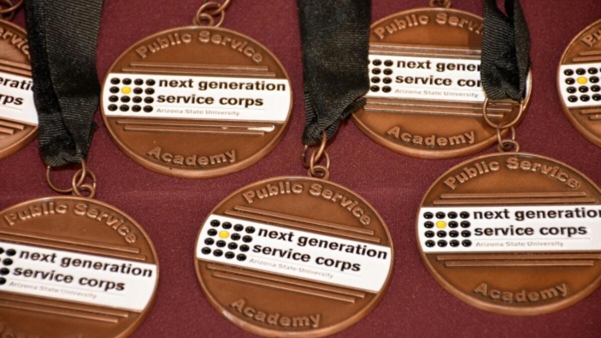 A table full of ASU Next Generation Service Corps medals with black ribbons.