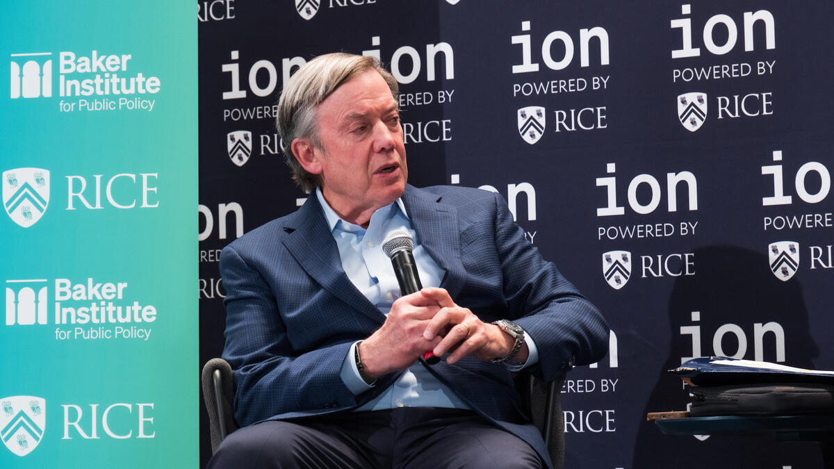 A person in business attire sits and speaks into a microphone on-stage during a fireside chat about US research universities.