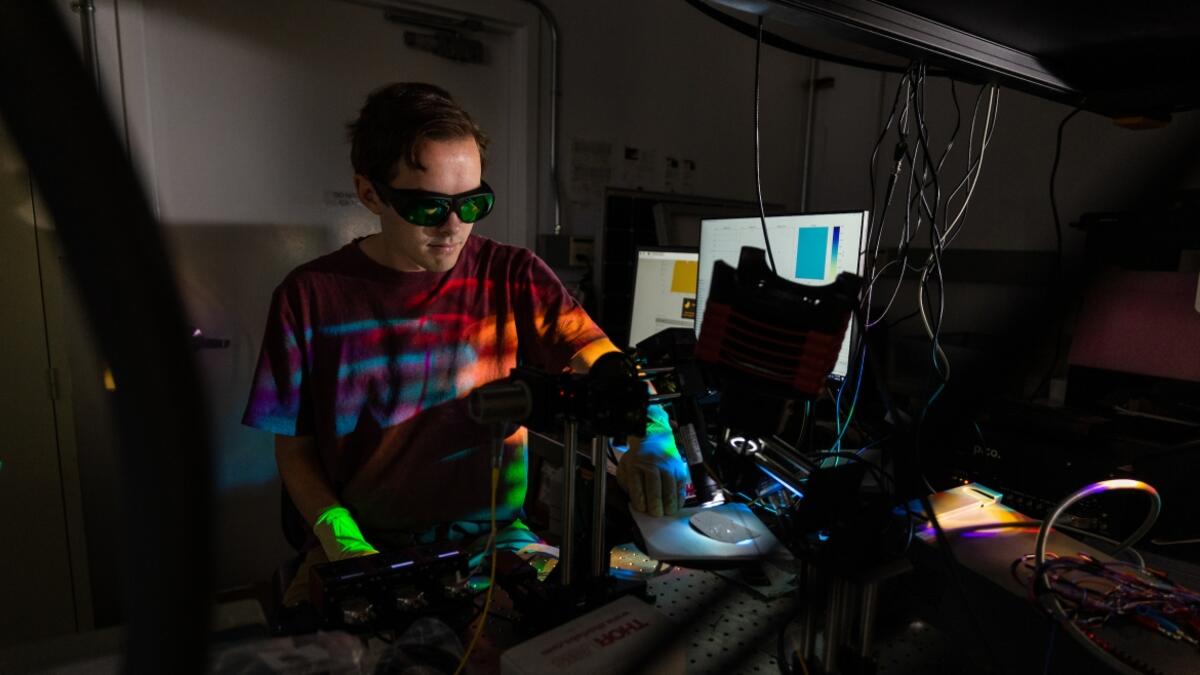 A person wearing protective eye wear and gloves tests semiconductors in a lab.