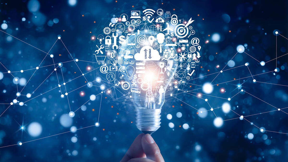 A hand holding up an imaginary lightbulb that is emitting images related to science and technology. 