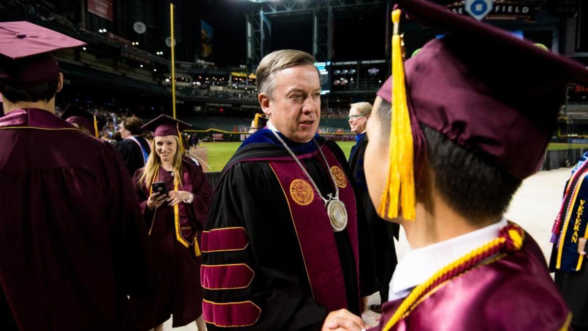 ASU President Michael Crow shakes hands with an ASU graduate at University Commencement